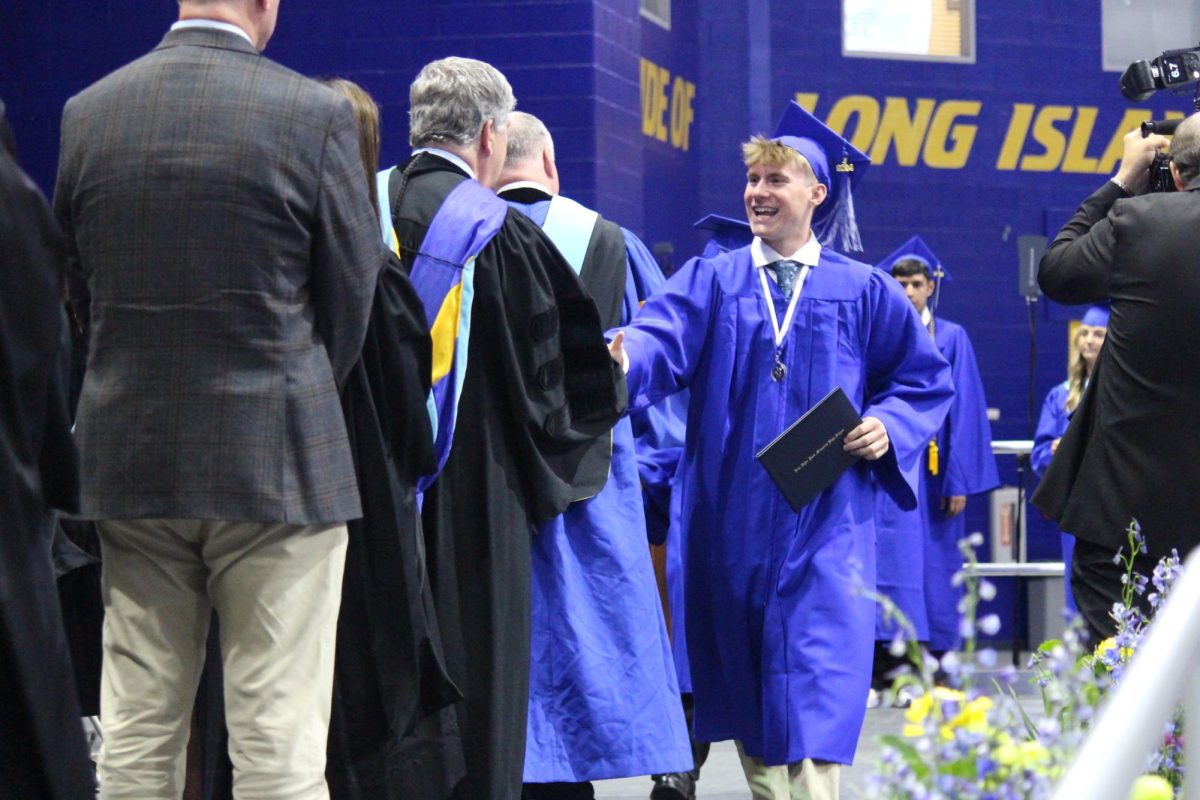 Graduates are called up one by one and embrace faculty members after receiving their diplomas.