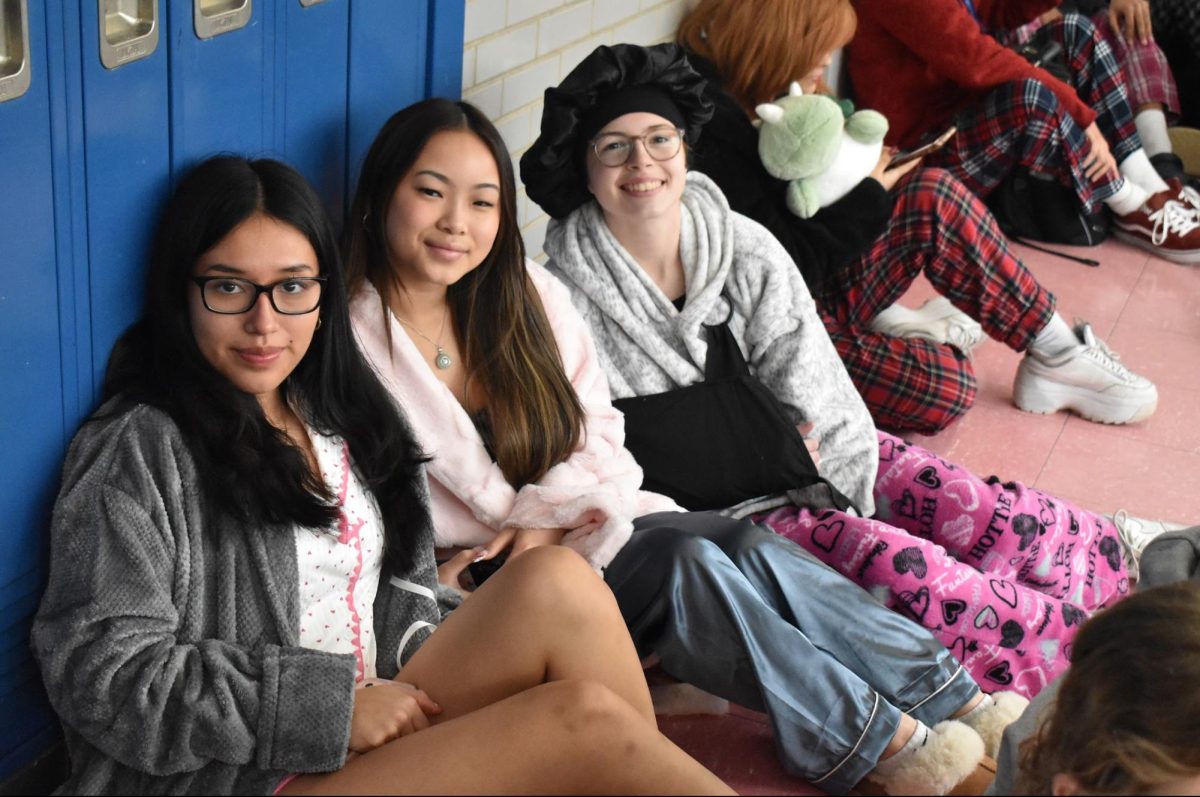 Seniors Kimberly Amon Segarra, Lauren Yip and Isabella Lugo pose sitting in the dead hallway.