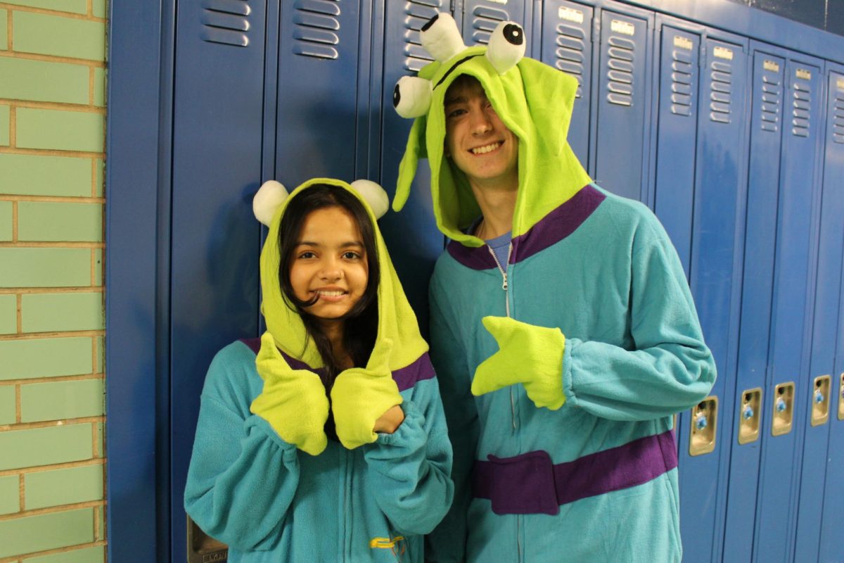 Dhara Patel and Matthew Batting stand together in their onesies. 